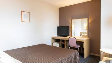 Une chambre d’hôtel comprenant un lit, un bureau avec un ordinateur et une télévision, une chaise, une petite table et un miroir.