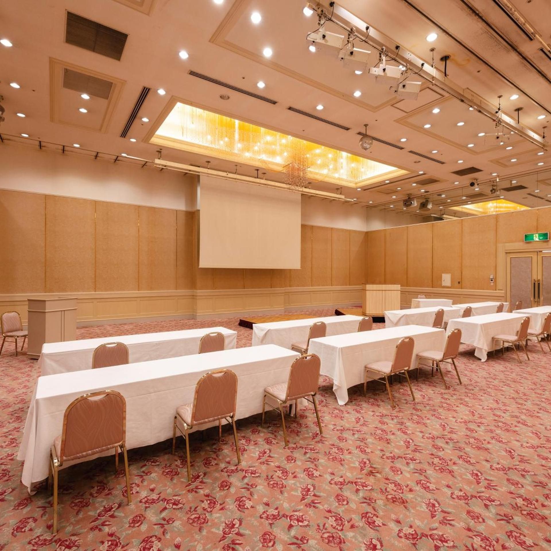 A conference room with multiple tables, chairs, and a presentation screen.