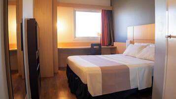 A hotel room with a bed, a desk, and a chair.