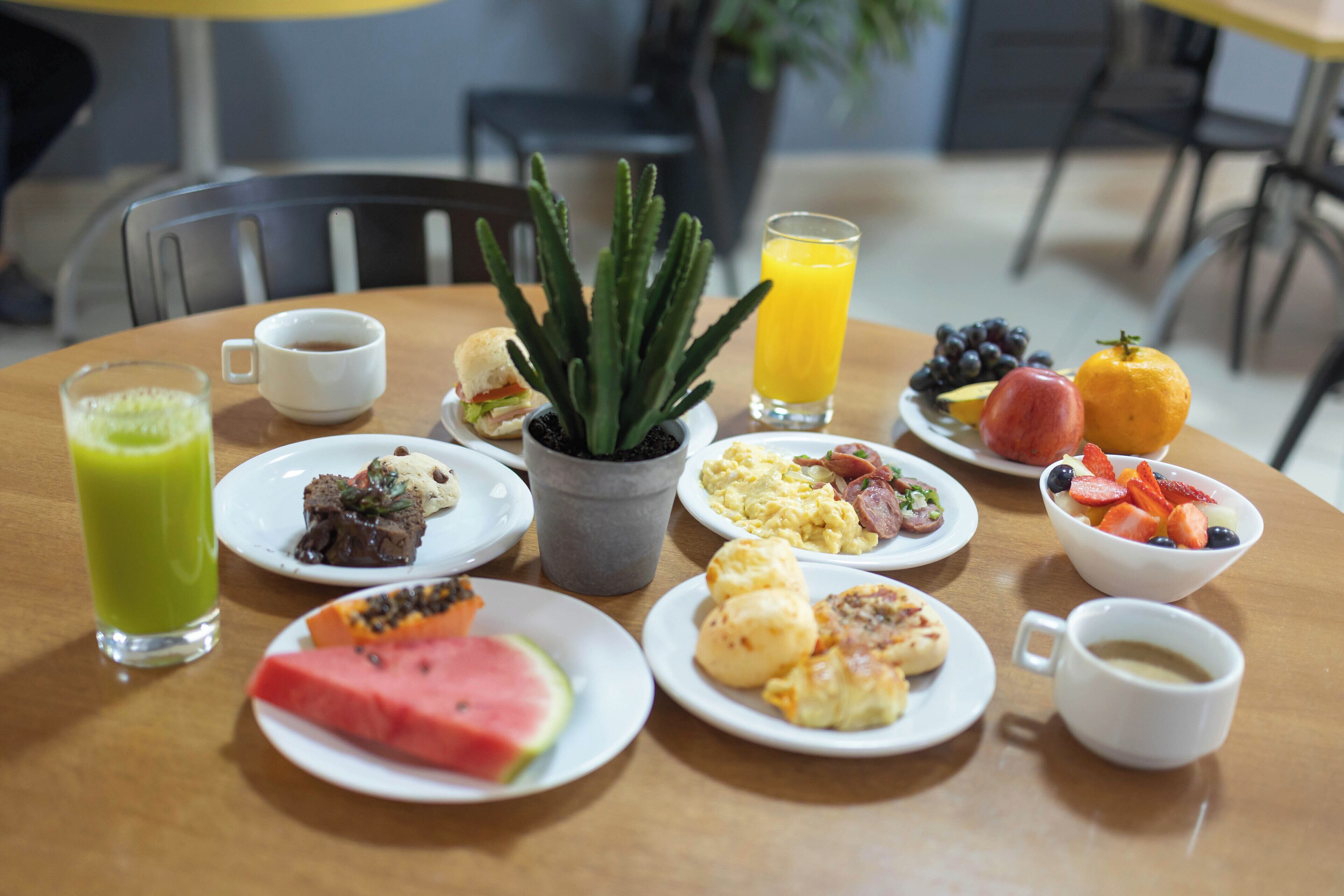 Et morgenbord med diverse retter, drikkevarer og en potteplante.
