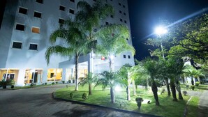 Un hotel con patio, palmeras y una entrada bien iluminada.
