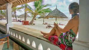 A beachside lounge with a thatched roof, palm trees, and a view of the beach. - Turtle Bay Beach Club (Watamu)