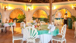 A dining area with round tables, white chairs, and a tropical theme. - Turtle Bay Beach Club (Watamu)