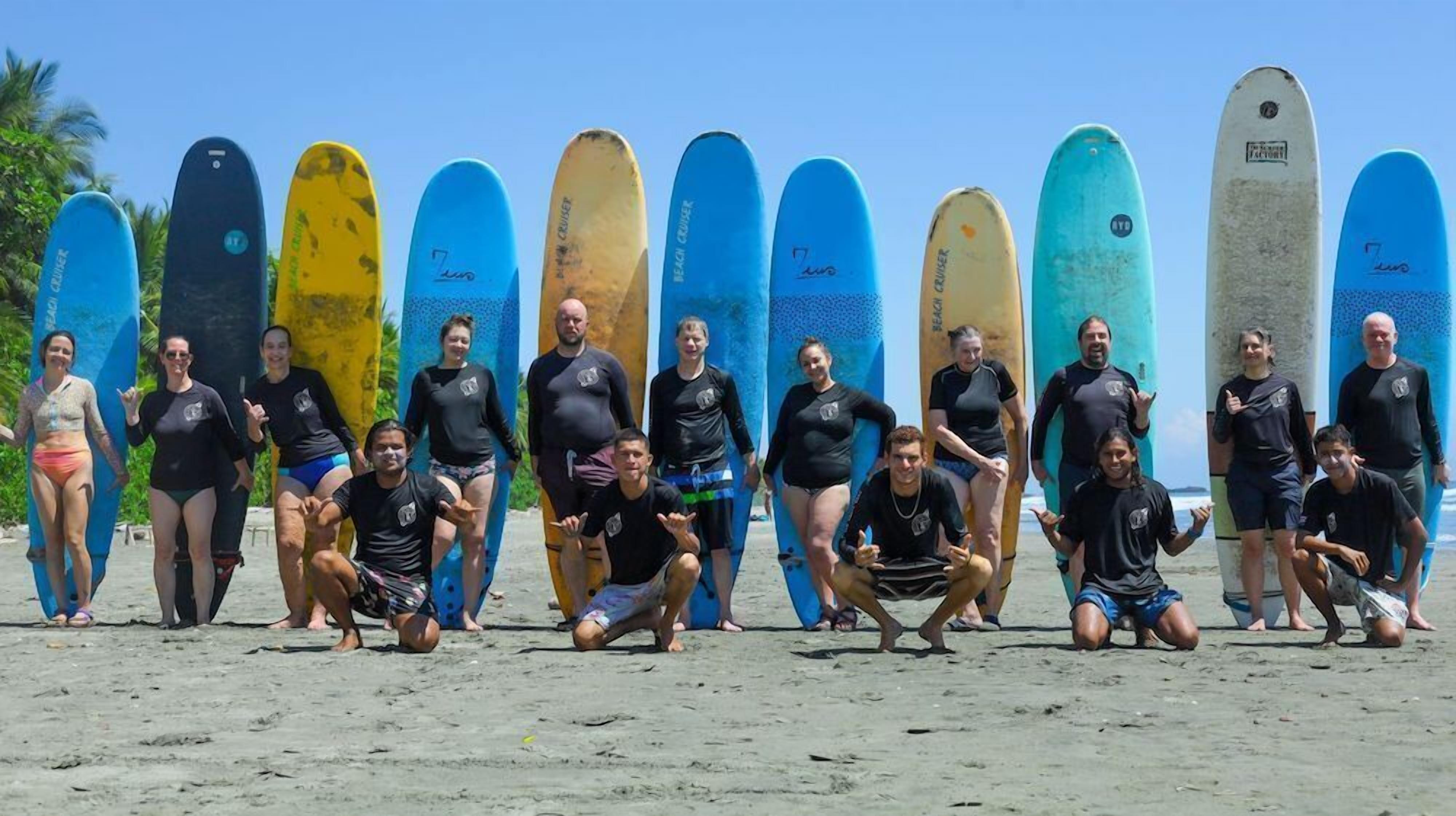 A group of people posing with surfboards on a sandy beach.