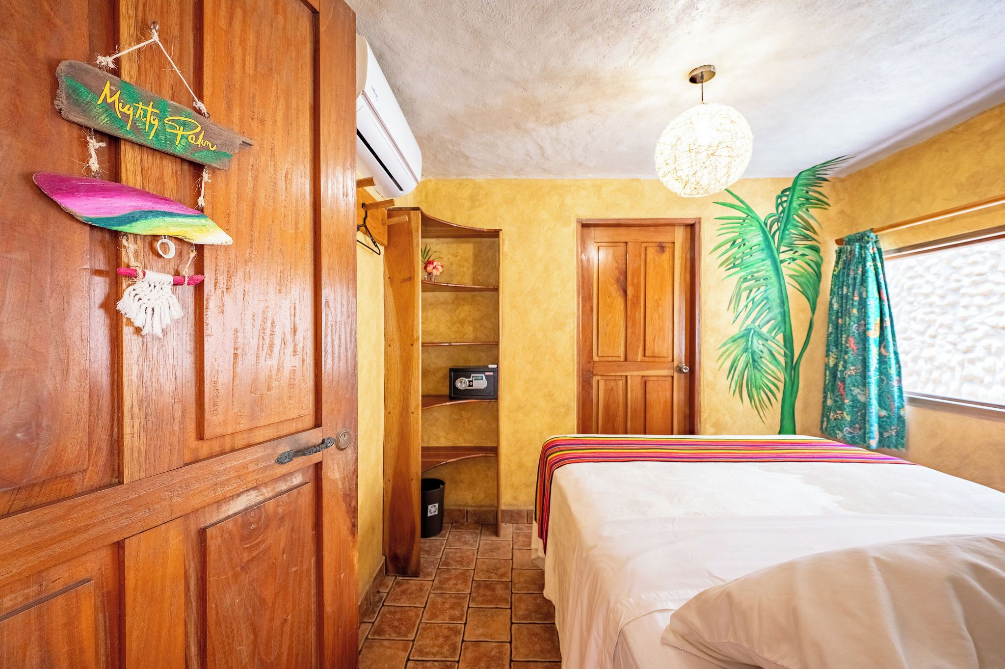 Ein Zimmer mit Holzboden, einem Bett, einem Regal mit einem dekorativen Gegenstand und einer Tür.
