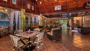 A spacious indoor area with high ceilings, wooden beams, and a variety of seating arrangements including tables and chairs. - El Sano Banano Beachside Hotel (Cóbano)