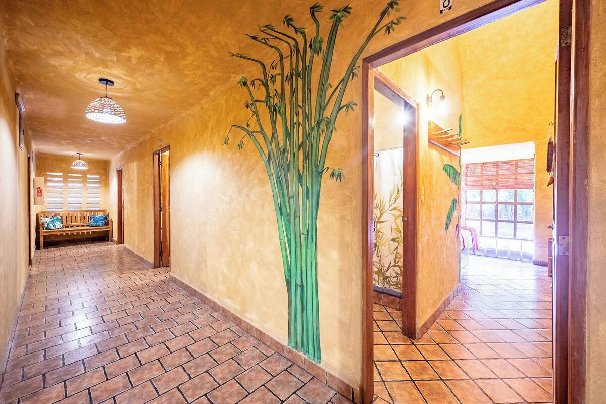 A hallway with a tiled floor, a bench, a wall with a bamboo mural, and a door leading to another room.
