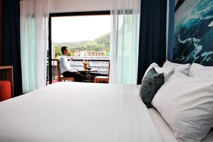 Habitación de hotel con una cama grande, vistas a un balcón y un cuadro en la pared.