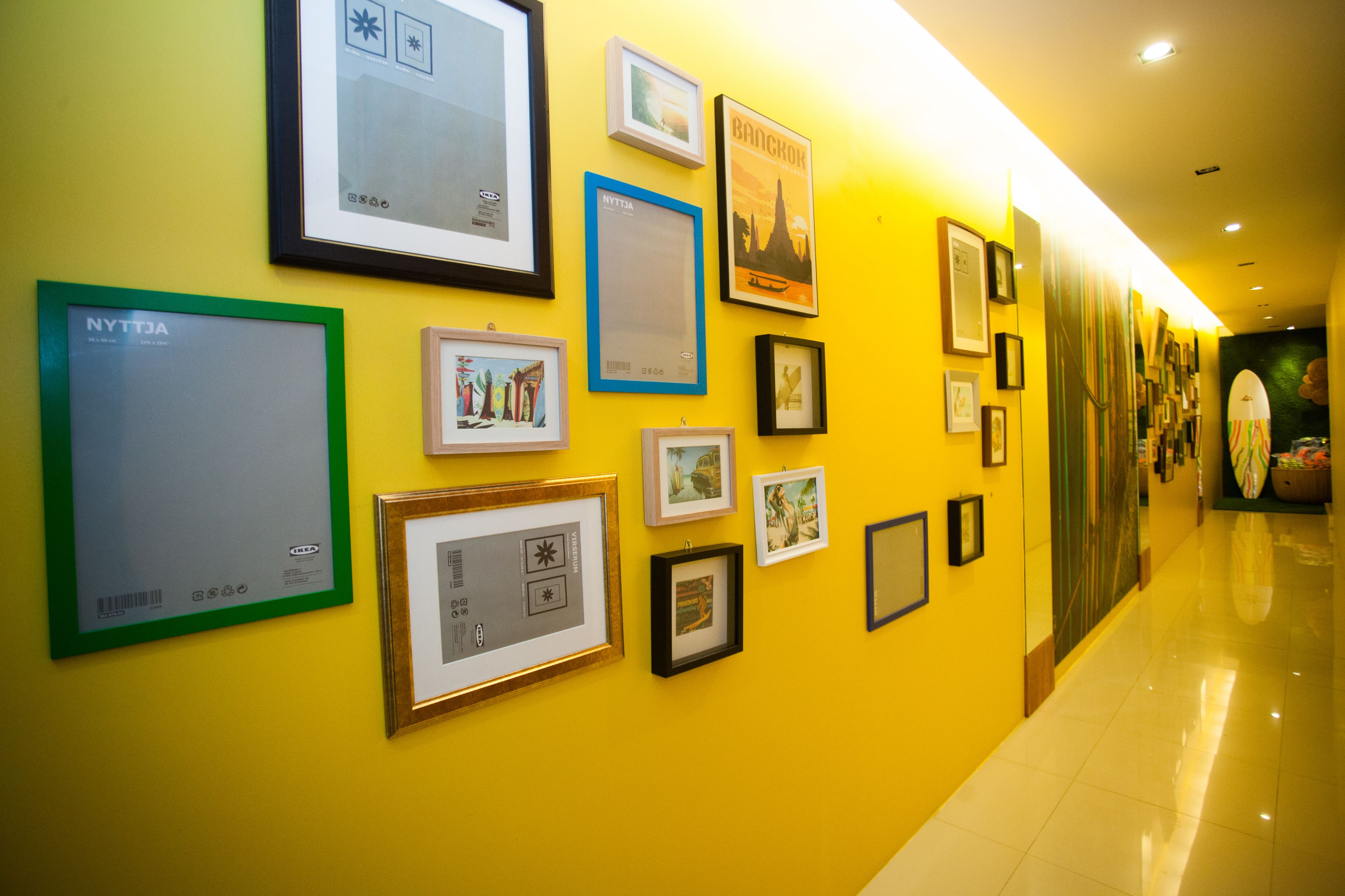 Un pasillo con obras de arte enmarcadas en las paredes, suelo pulido y una pared de color amarillo brillante.
