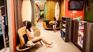 Vestíbulo de hotel con mostrador de recepción, zona de estar y tablas de surf exhibidas.