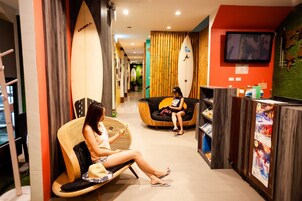 Vestíbulo de hotel con mostrador de recepción, zona de estar y tablas de surf exhibidas.