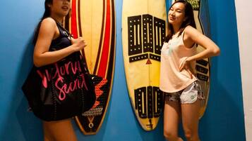 Two people standing in front of surfboards on a blue wall.