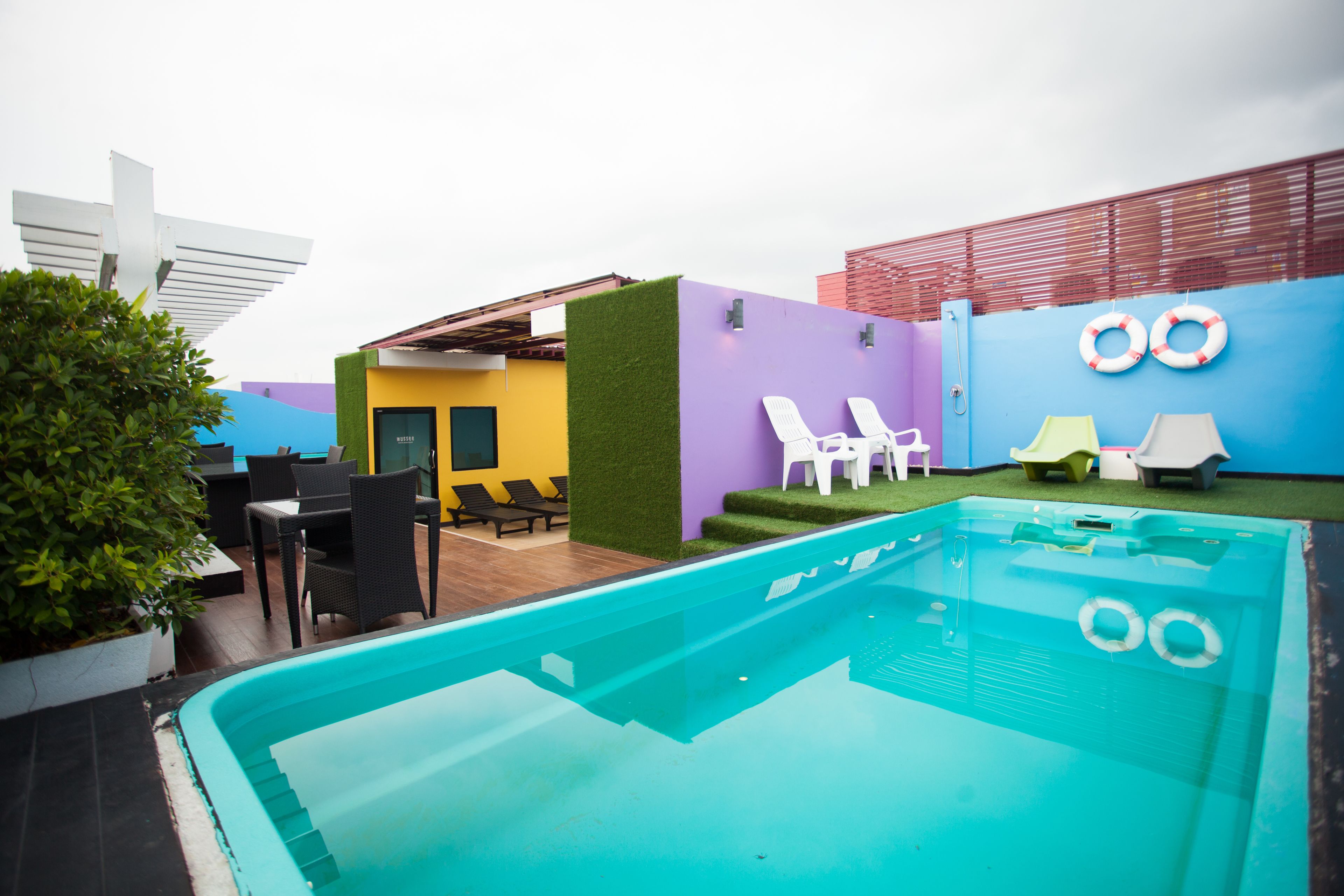 A swimming pool with lounge chairs and a small patio area with a table and chairs.