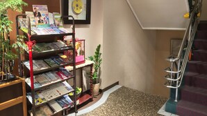 A hotel lobby with a staircase, a bookshelf with magazines, and a framed picture on the wall. - FuZhuang Hotel (Taipei)