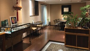 A well-lit room with a reception desk, chairs, a table, and potted plants. - FuZhuang Hotel (Taipei)