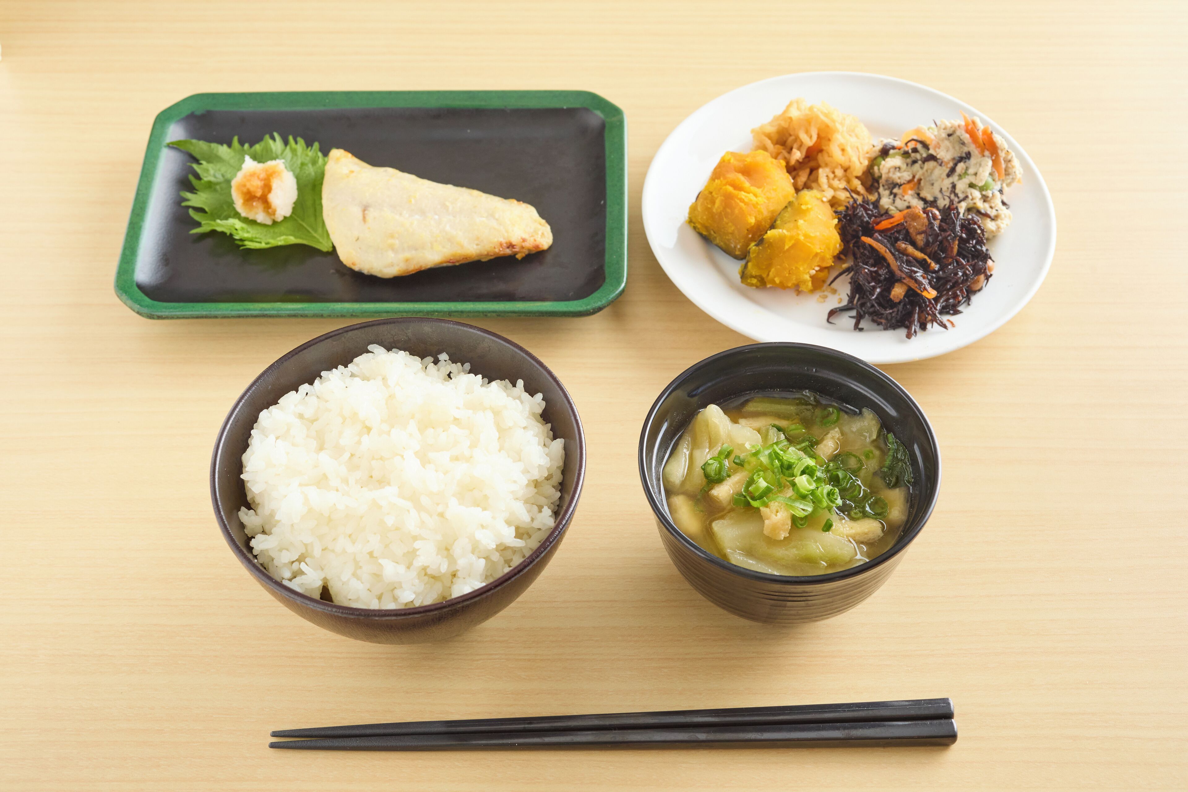 A meal consisting of rice, soup, and a plate with various dishes.