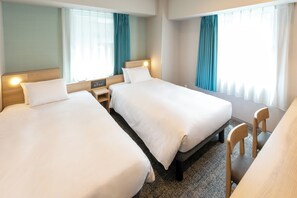 Une chambre d’hôtel avec deux lits, un bureau et une chaise.