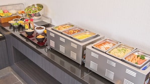 Un bufé con diversas opciones de comida, como ensaladas, granos y carnes.