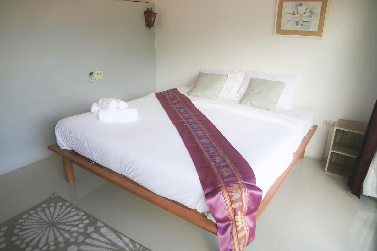 Una cama bien hecha con sábanas blancas y un cojín decorativo morado.