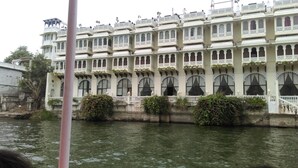 Un edificio de varios pisos con balcones y ventanas arqueadas, junto a una masa de agua.