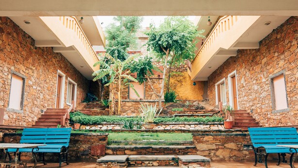 Un patio con muros de piedra, una escalera central y dos bancos azules.