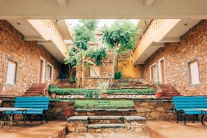 Un patio con muros de piedra, una escalera central y dos bancos azules.