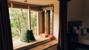 Un dormitorio con ventanal, cama y mesita de noche.