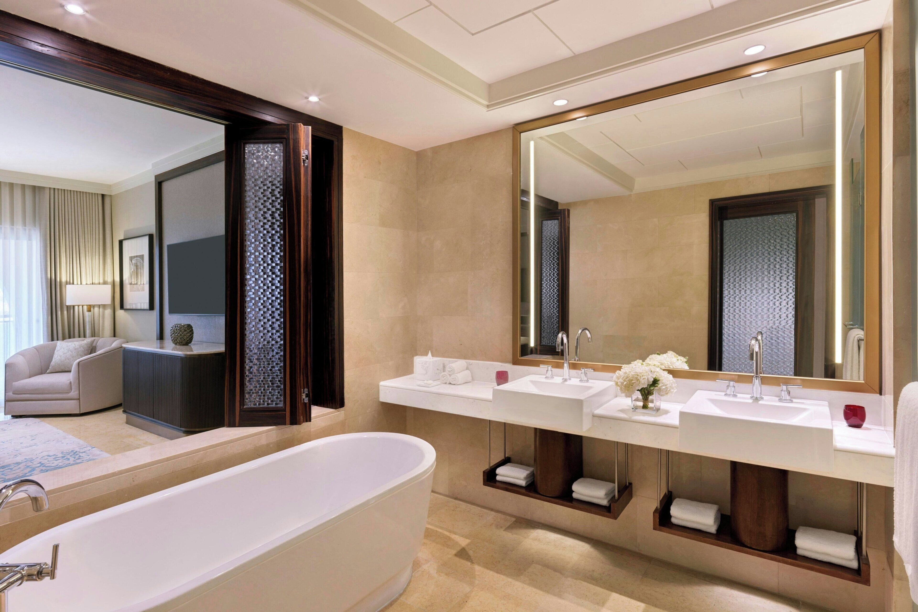 Un baño moderno con una bañera grande, dos lavamanos y un espejo amplio.