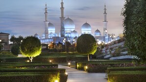 Une mosquée dotée de plusieurs dômes et de plusieurs minarets, entourée de jardins et de sentiers parfaitement entretenus.