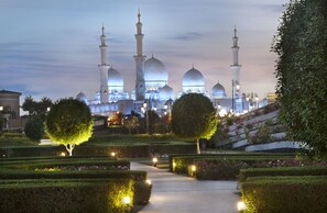 Une mosquée dotée de plusieurs dômes et de plusieurs minarets, entourée de jardins et de sentiers parfaitement entretenus.