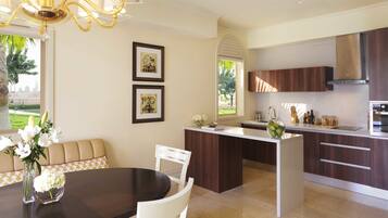A modern kitchen with a central island, white cabinetry, and a dining area with a table and chairs.