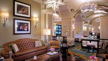 Um hall de hotel luxuoso com um sofá marrom macio, um bar e elegantes lustres.
