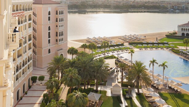 Un hôtel doté d’une piscine, de palmiers et offrant une vue sur l’eau.