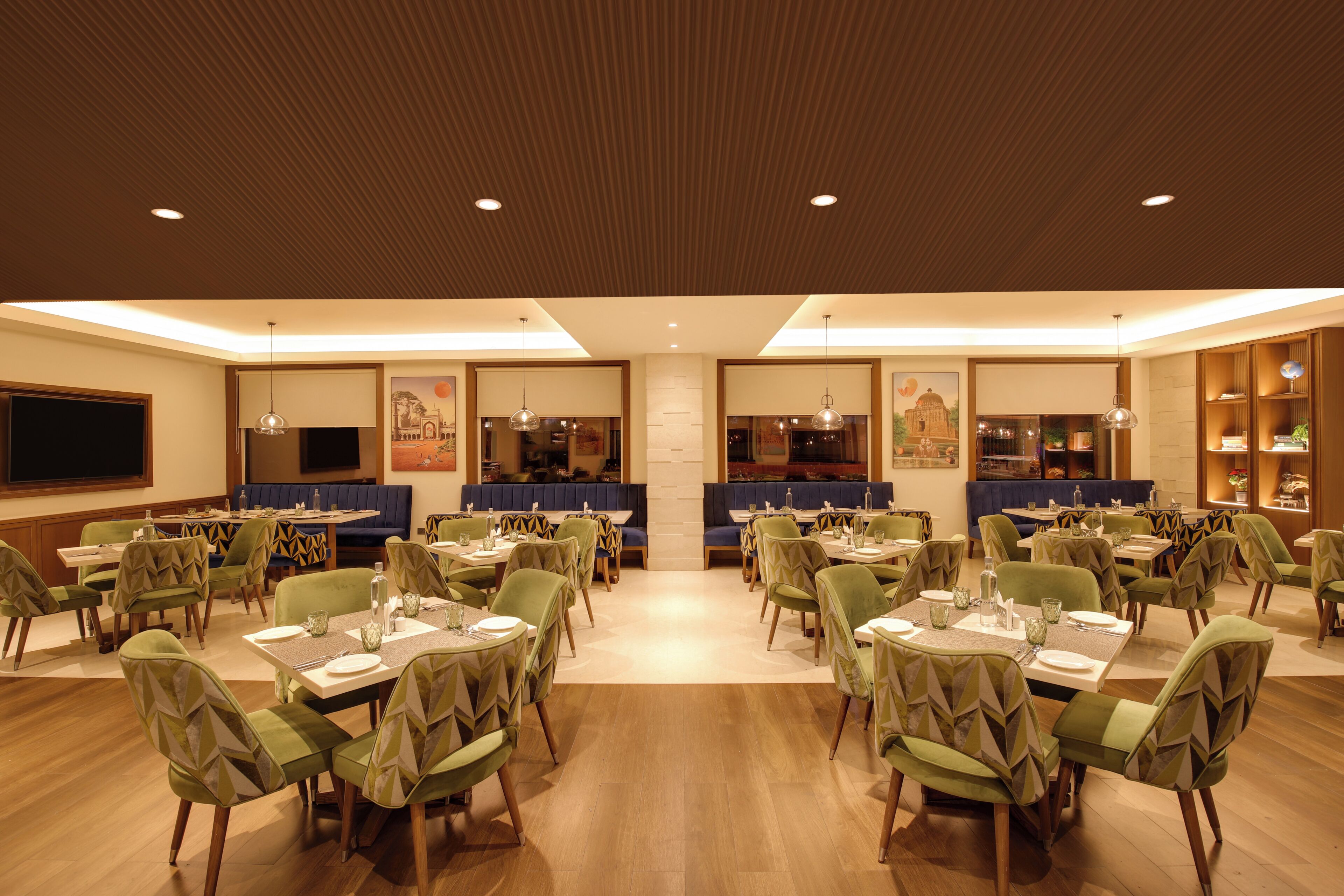 A spacious dining area with multiple tables and chairs, a central seating area with a blue booth, and a wall-mounted television.