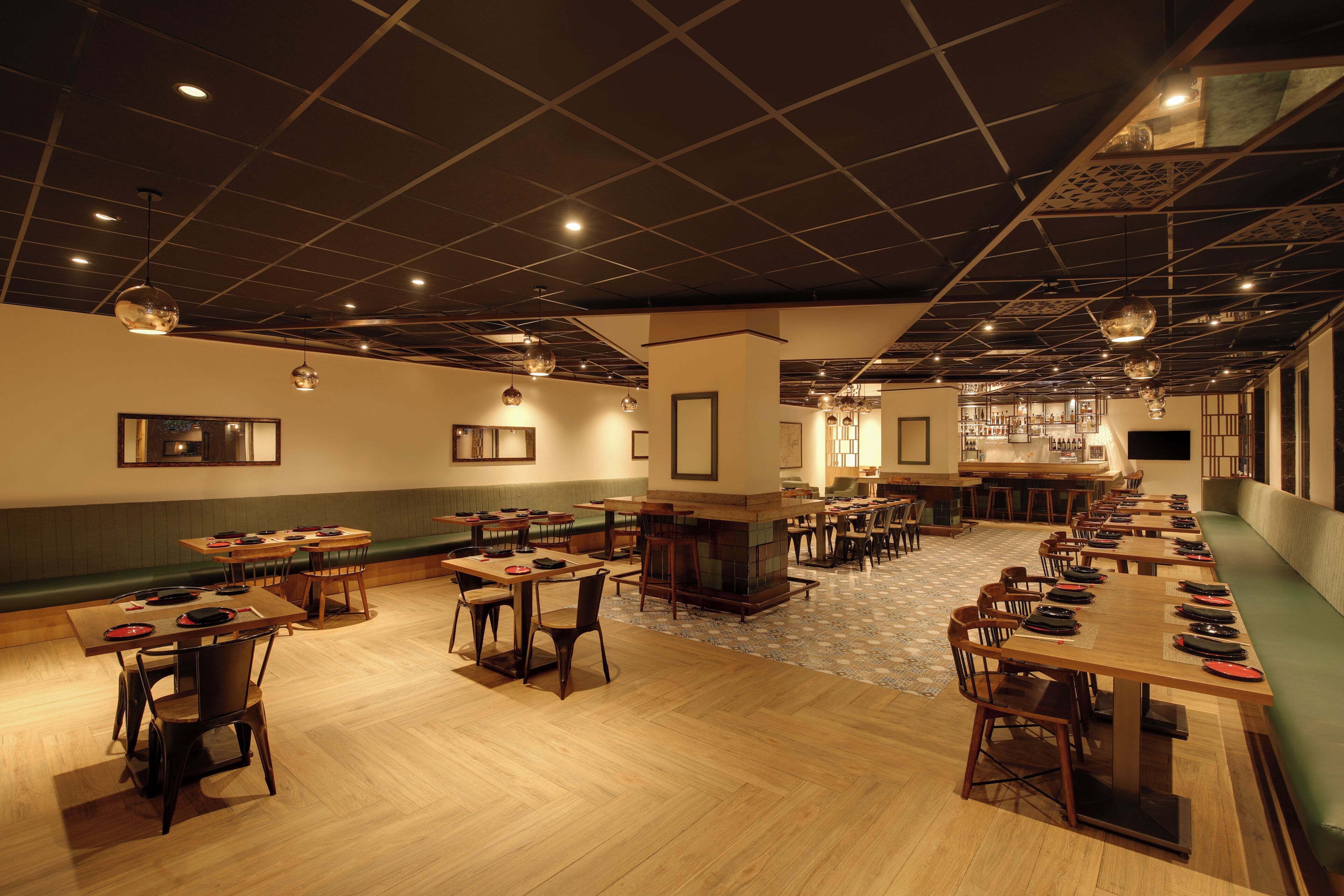 A spacious restaurant with multiple tables and booths, a bar area, and a patterned floor.