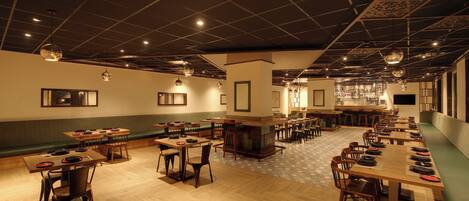 A spacious restaurant with multiple tables and booths, a bar area, and a patterned floor.