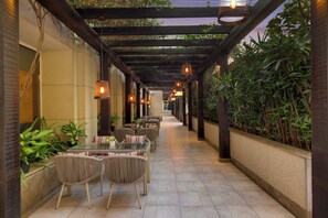 A covered outdoor dining area with wicker furniture and hanging lights. - Lemon Tree Premier, Delhi Airport (New Delhi)