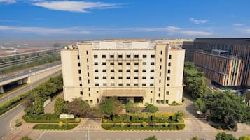 A large building with a central courtyard, surrounded by trees and a road.