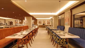 Una larga mesa de comedor con varias sillas, una zona de cocina y un área de estar con sofá.