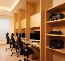 A modern office with wooden paneling, desks with computers, and office chairs.
