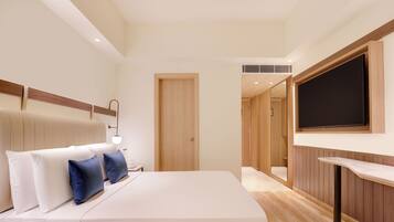 Ein modernes Hotelzimmer mit Bett, Nachttisch und flachbildfernseher an der Wand.