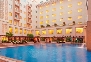 A hotel with a large indoor pool, multiple balconies with plants, and a modern architectural design.