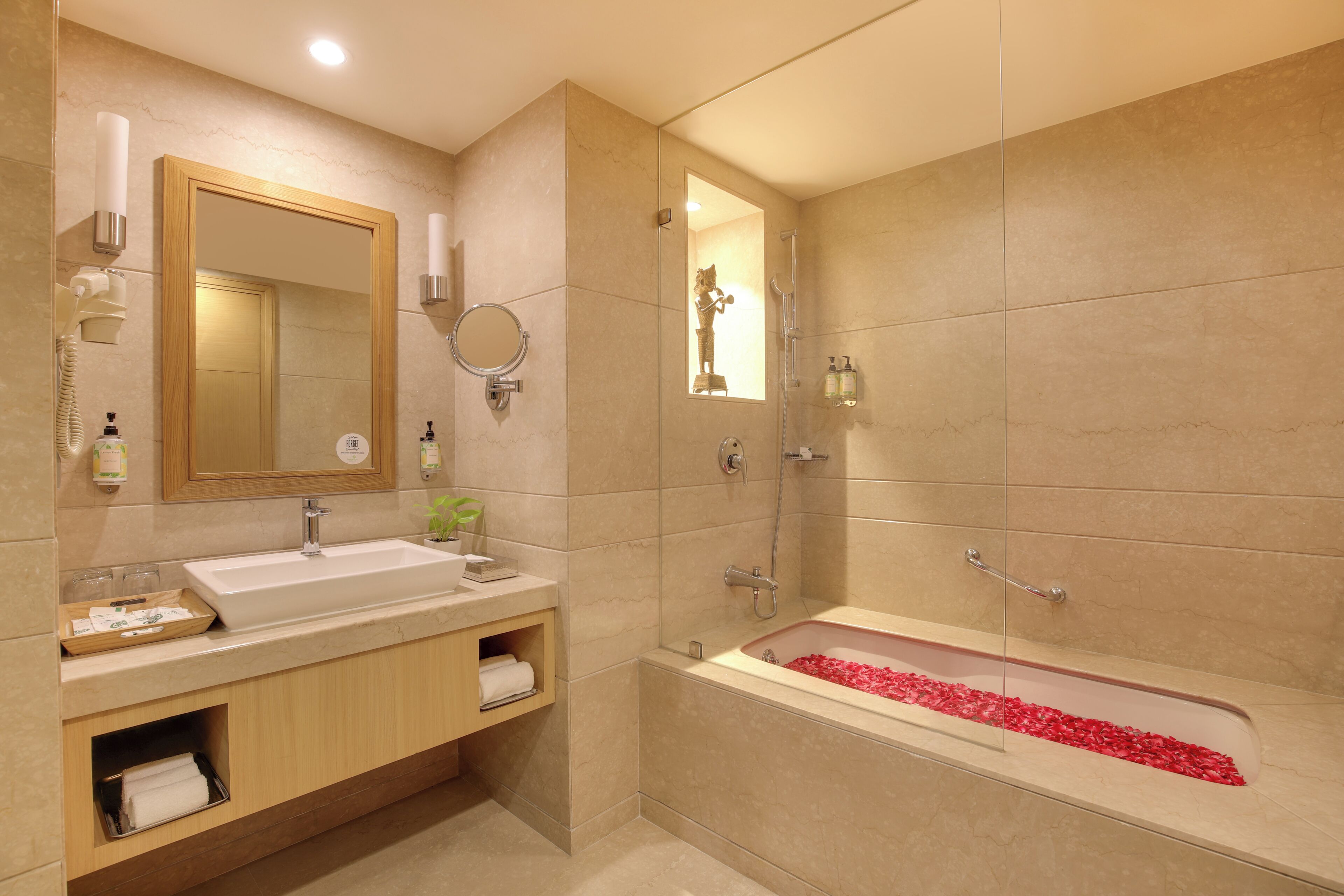 A modern bathroom with a large sink, a bathtub with rose petals, a mirror, and a shower.