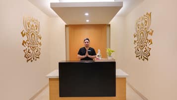 A reception desk with a person standing behind it, a wooden panel wall, and decorative wall art.