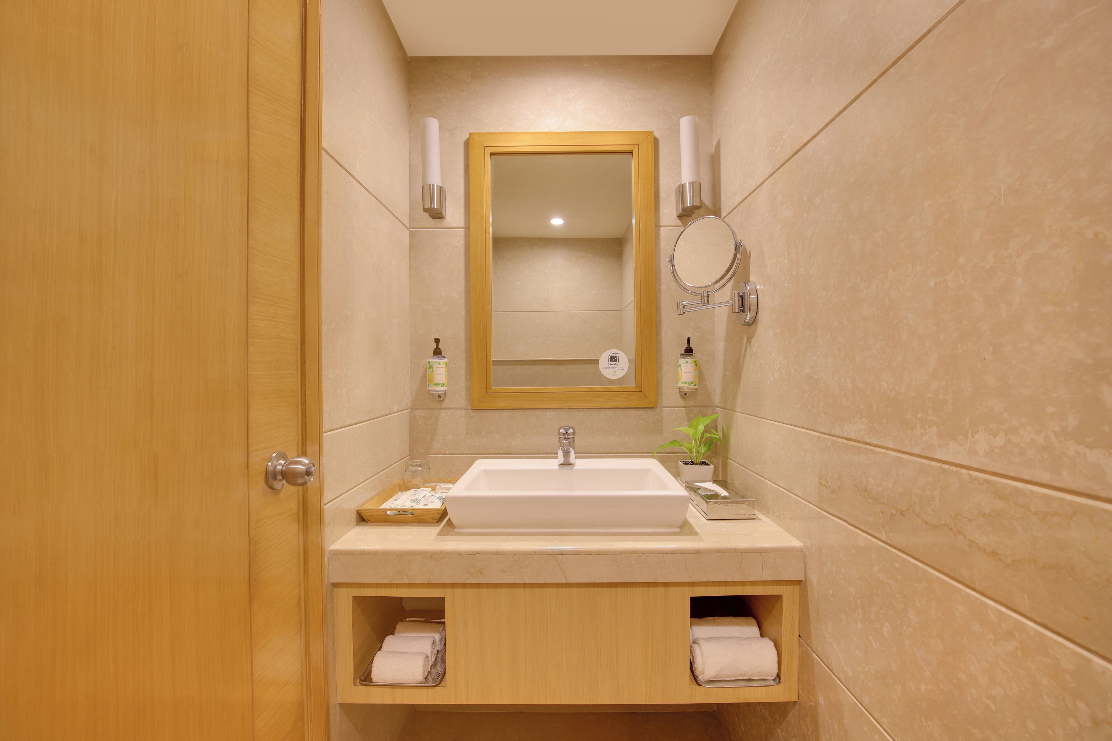 A bathroom with a wooden door, a white sink, a mirror, and two towel racks.