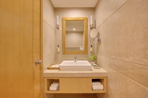 Un bagno con una porta in legno, un lavandino bianco, uno specchio e due portasci.