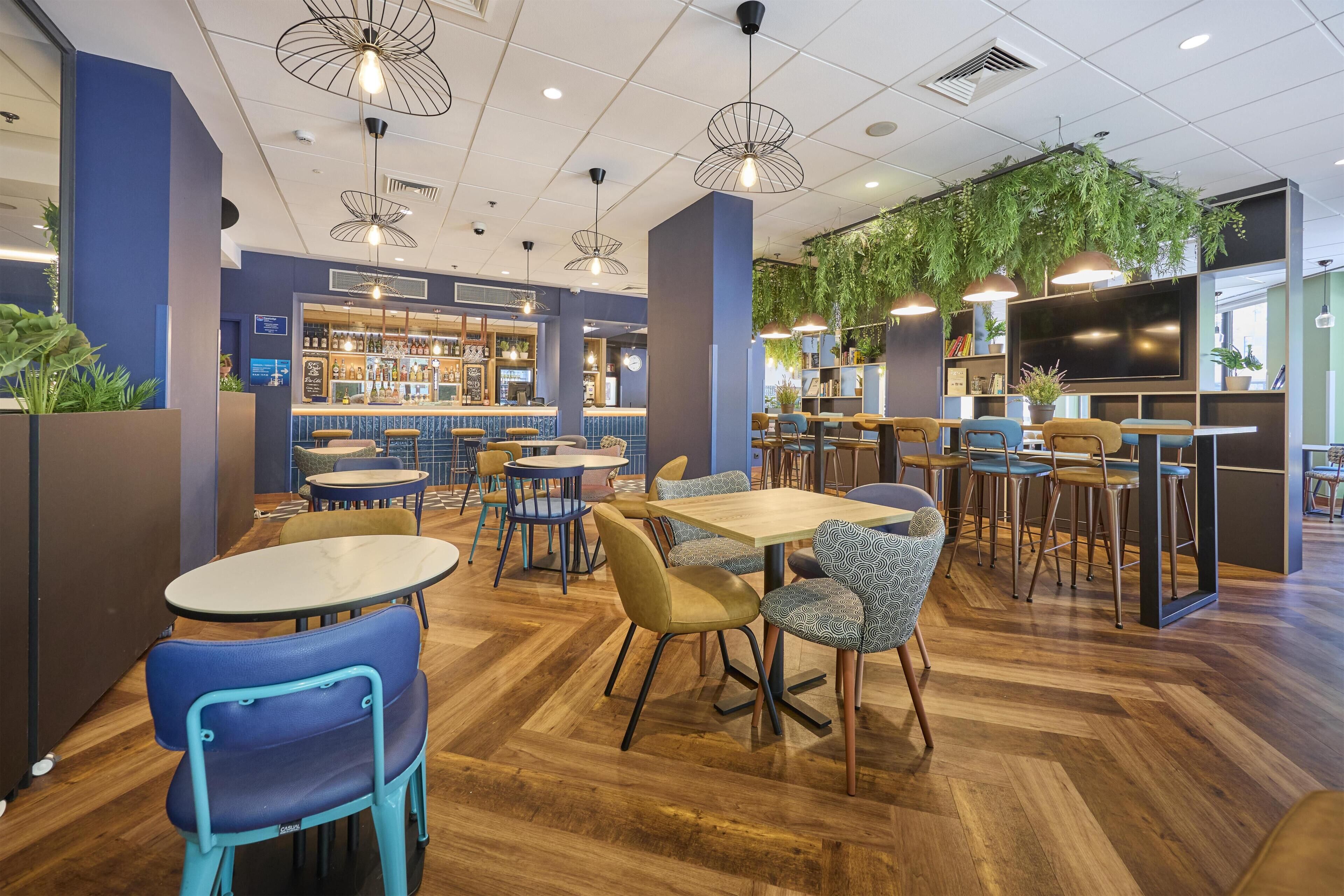 A modern bar area with seating, a television, and a green wall.