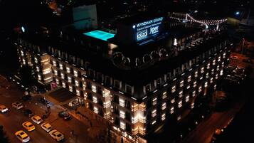 A multi-story hotel with a prominent rooftop pool and illuminated signage.