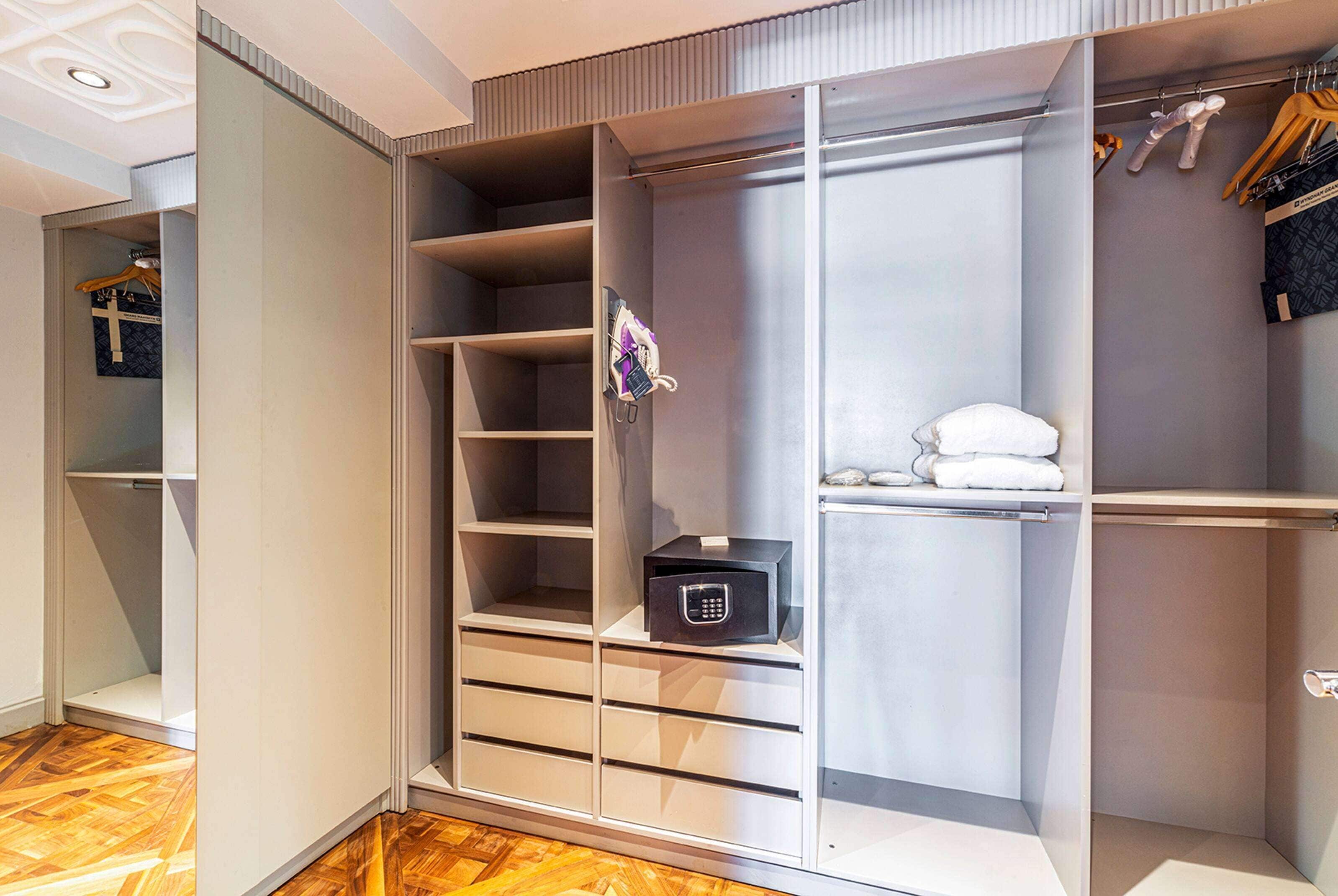 Un armario vestidor con amplios estantes, cajones, una barra para colgar y una caja fuerte.