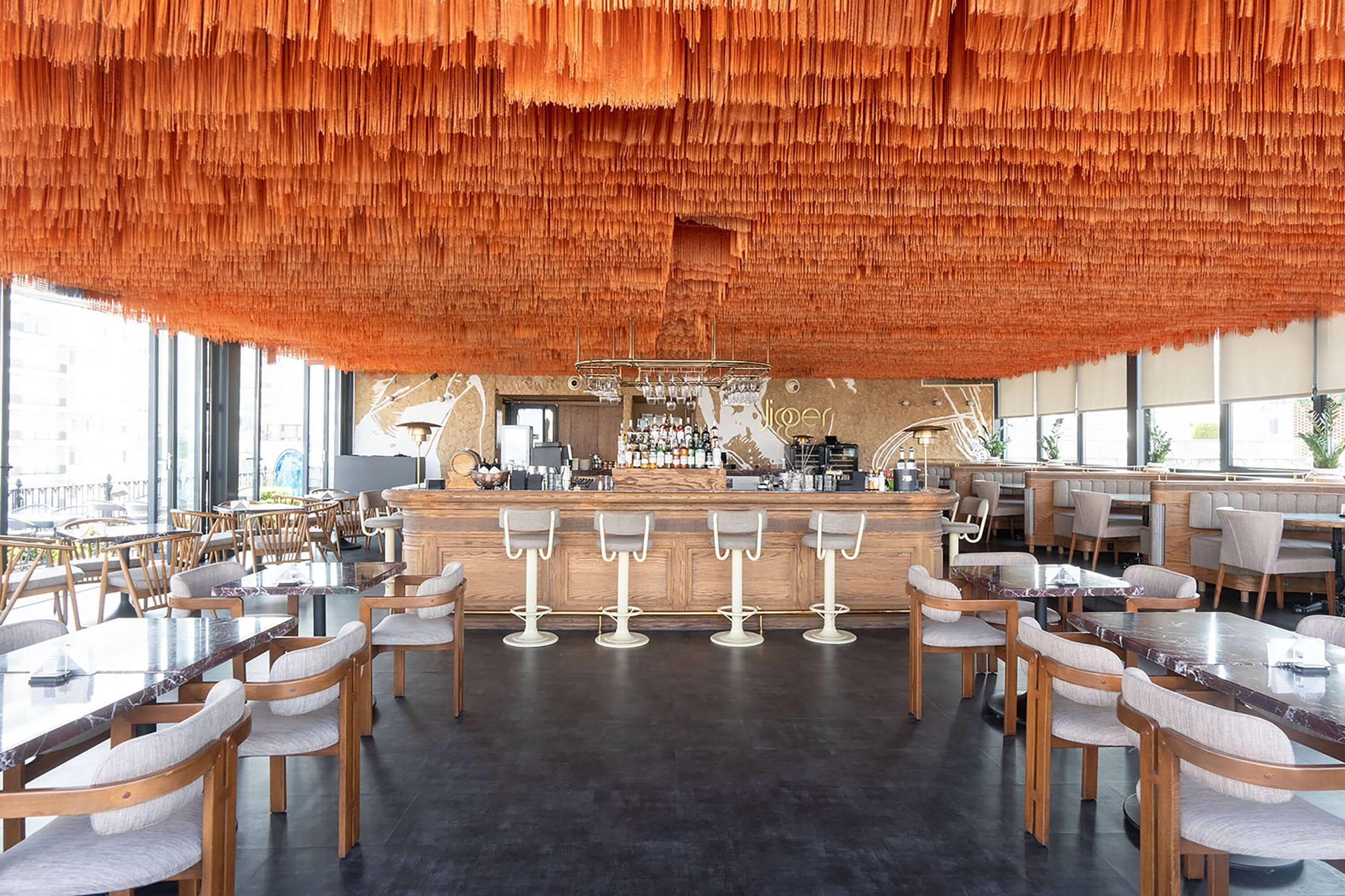 A modern bar area with wooden furniture and a unique orange hanging decor.